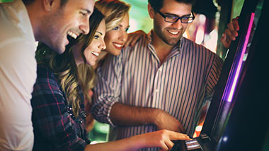 Four young people playing a slot machine at Argosy Casino Alton.